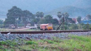 Dizel lokomotifler, Lamphun Tren İstasyonu 'nda durmak için raylar üzerinde çalışır. Bu çekim Tha Chomphu Beyaz Köprüsü 'nde günbatımında çekildi..