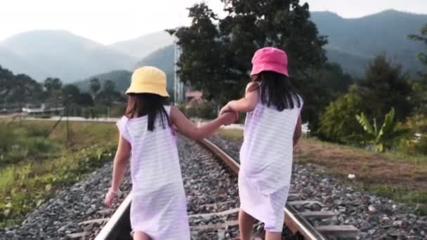 Két Aranyos Ázsiai Lány Fut Együtt Vasúti Síneken Vidéken Hegyekkel — Stock videók