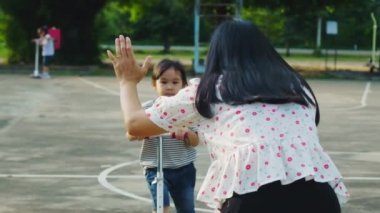 Mutlu anne ve çocuklar yaz parkında scooter sürerken beşlik çakıyorlar. Çocuklar dışarıda scooterlarla oynuyor. Çocuklar için boş zaman aktiviteleri ve açık hava sporları