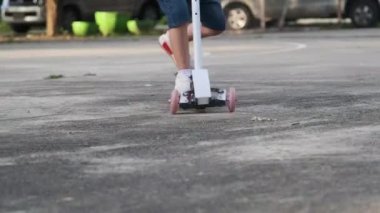İki küçük tatlı kız yaz günü parkta motosikletle geziyorlar. Çocuklar dışarıda scooterlarla oynarlar. Çocuk için aktif eğlence ve açık hava sporu