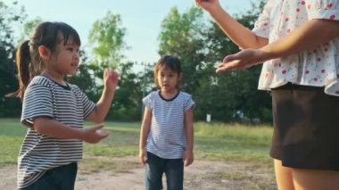 Anne ve çocuklar parkta birlikte oynuyorlar. Mutlu aile tatilde birlikte aktiviteler yapıyor..
