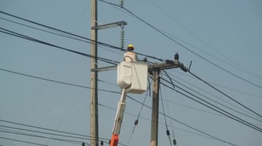 Asansör kovasında elektrik işçisi kabloları kurmak ve onarmak için elektrik direği üzerinde çalışıyor..