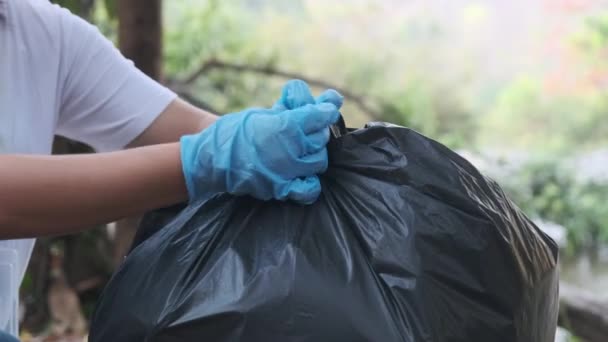 川でゴミを拾い ゴミ袋を結ぶ女性ボランティアの手 環境を救うためにゴミ箱にゴミを入れてください 世界環境デー — ストック動画