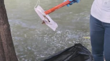 Asyalı gönüllü aileler nehir kenarında çöp ve plastik topluyorlar. Çevreyi kurtarmak için çöpü çöpe atın. Dünya Çevre Günü