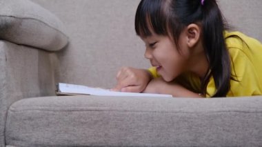 Evdeki kanepede oturmuş kitap okuyan tatlı küçük kız..