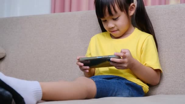 Menina Bonito Jogar Jogos Online Seu Smartphone Sentado Sofá Casa — Vídeo de Stock