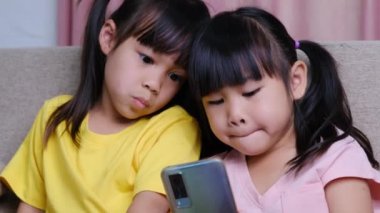 İki kız kardeş akıllı telefonlarıyla evdeki kanepede selfie çekiyorlar..