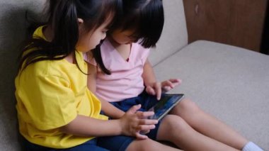 İki kız kardeş akıllı telefonlarıyla evdeki kanepede selfie çekiyorlar..