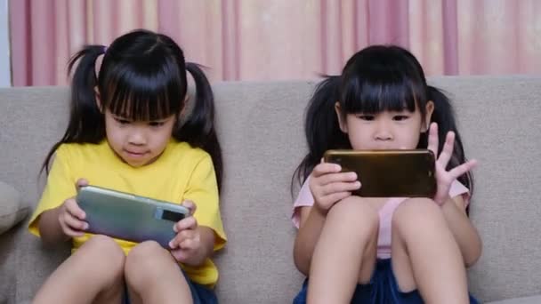 Две Сестры Играют Онлайн Игры Своих Смартфонах Сидя Дома Диване — стоковое видео