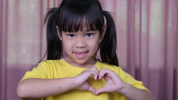 愛とケアを示す手で心のジェスチャーを作るかわいい女の子 愛のシンボルを示す健康な笑顔の女の子 — ストック動画