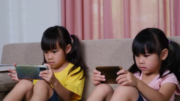 Dos Hermanas Están Jugando Juegos Línea Sus Teléfonos Inteligentes Sentadas — Vídeo de stock