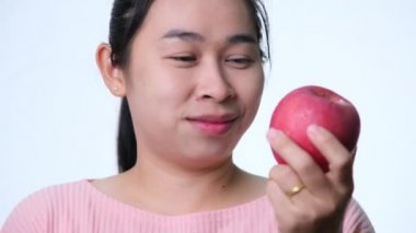 Elmalı bir elma tutan Asyalı kadın ve güçlü dişler gösteren bir gülümseme.