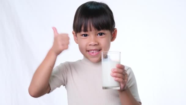 Asiática Niña Linda Bebiendo Leche Vaso Sonrisa Sobre Fondo Blanco — Vídeo de stock