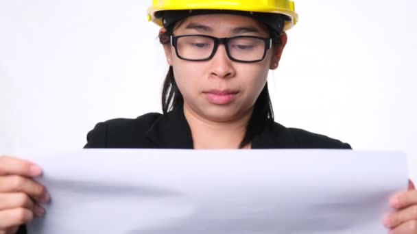 戴着头盔的女建筑师在工作室里看着白色背景的建筑计划 漂亮的女土木工程师 看蓝图 看草图 — 图库视频影像