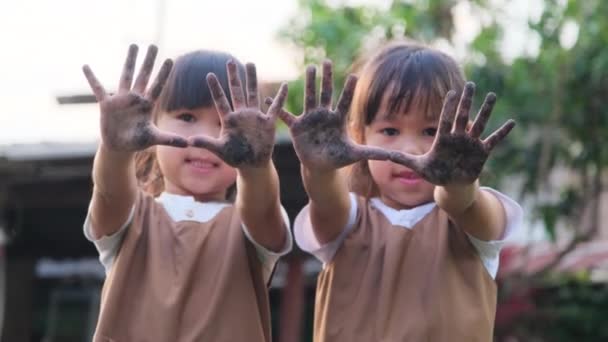 亚洲兄弟姐妹们在花园里玩耍 炫耀他们肮脏的泥巴手 — 图库视频影像