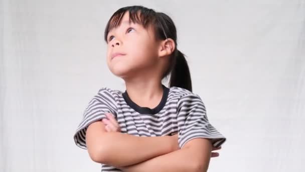 Χαριτωμένο Κοριτσάκι Που Κοιτά Σταυρωμένα Χέρια Και Σκέφτεται Κάτι Λευκό — Αρχείο Βίντεο