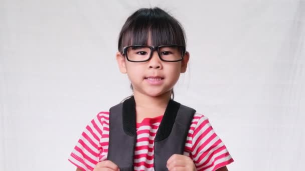 Aranyos iskolás lány visel szemüveg hátizsák, ő szép, bájos és élvezi a jó hangulatot a fehér háttér stúdióban. Vissza az iskolába