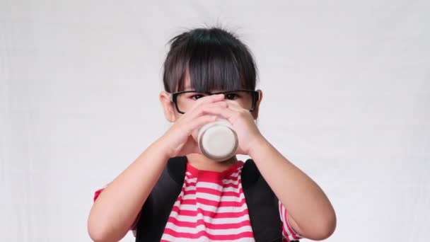 学校に行く前にガラスから牛乳を飲むかわいい女子高生 子供のための健康的な栄養 学校のコンセプトに戻り — ストック動画