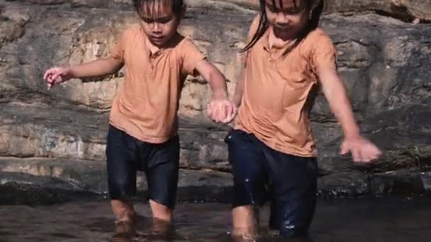 아시아 소녀가 여동생 속에서 있습니다 여름철에 아이들 강에서 오락을 즐기는 — 비디오