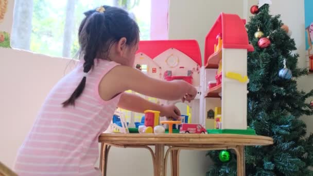 快乐的小女孩玩塑料娃娃房子与迷你家具玩具和娃娃 穿着粉红衣服的可爱的小女孩在儿童房里很开心 — 图库视频影像