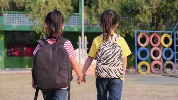 两个穿着夏装背着背包的可爱的女学生一起在学校里散步 从后面看 回到学校的概念 — 图库视频影像