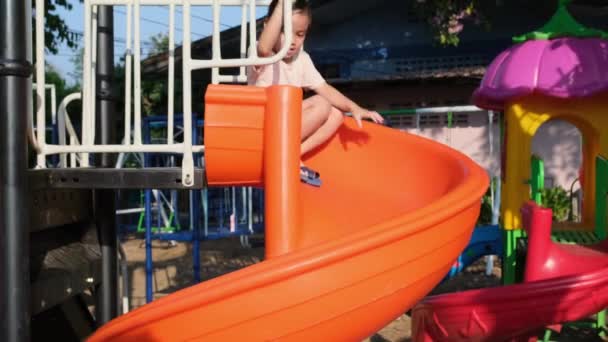 屋外の遊び場でアクティブな小さな女の子 かわいい女の子がスライダーで滑り降りる 子供のための健康的な夏の活動 — ストック動画