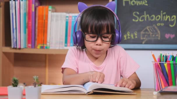 Χαριτωμένο Κοριτσάκι Ακουστικά Ακούει Audiobooks Και Κοιτάζοντας Αγγλικά Βιβλία Μάθησης — Αρχείο Βίντεο