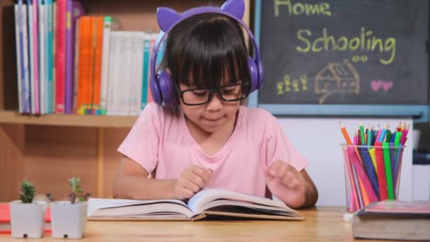 Nettes Kleines Mädchen Mit Kopfhörern Das Hörbücher Hört Und Englisch — Stockvideo