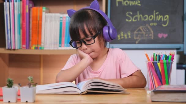 Słodka Dziewczynka Słuchawkami Słuchająca Audiobooków Patrząca Angielskie Książki Nauki Stole — Wideo stockowe