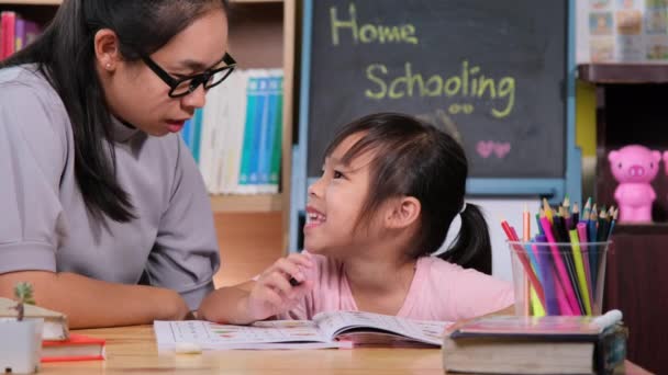 アジア系の少女は母親と隔離中に家で勉強する 母は家で娘の宿題を手伝っている 家庭教育 — ストック動画