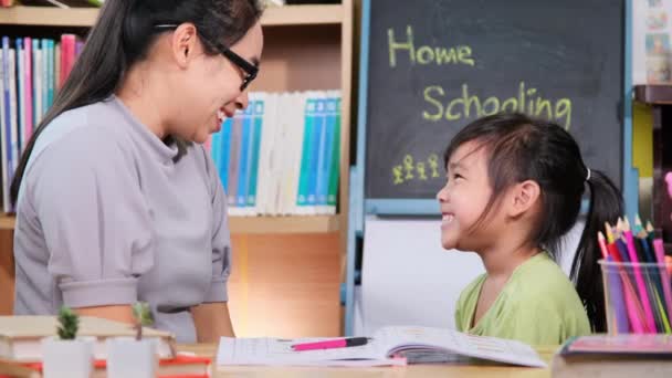 アジア系の少女は母親と隔離中に家で勉強する 母は家で娘の宿題を手伝っている 家庭教育 — ストック動画