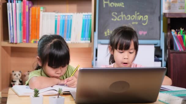 2人のアジアの女性学生が自宅でノートパソコンでオンラインビデオ通話ズームを勉強します 隔離中に家で学ぶ2人の少女 新常態 家庭教育 — ストック動画