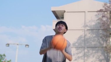 Genç Asyalı atletik erkek dışarıda basketbol oynuyor. Genç sporcular dışarıda basketbol oynuyorlar..