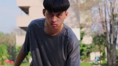 Genç Asyalı atletik erkek dışarıda basketbol oynuyor. Genç sporcular dışarıda basketbol oynuyorlar..