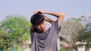 Sağlıklı genç adam parkta koşmadan önce ısınmak için esniyor. Sporda dinamik egzersiz ve kardiyo eğitimi kavramı.