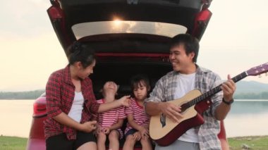 Mutlu aile yaz tatilinde araba yolculuğunun tadını çıkarıyor. Anne ve çocuk arabanın bagajında oturup babamın gitar çalmasıyla birlikte şarkı söylüyorlar. Tatil ve seyahat aile kavramı.