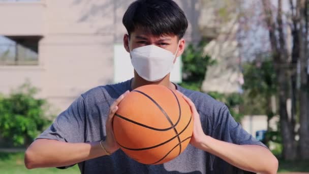 Joven Asiático Con Una Máscara Facial Sosteniendo Una Pelota Baloncesto — Vídeo de stock