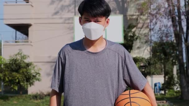 Ung Asiatisk Man Med Ansiktsmask Som Håller Basket Händerna Friluftsplan — Stockvideo