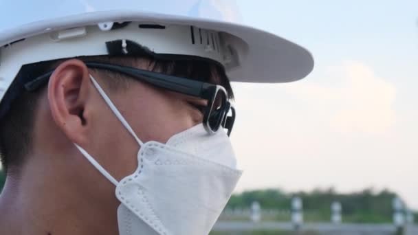 Молодой Азиатский Инженер Шлеме Маске Смотрит Улыбается Камеру Заднем Плане — стоковое видео