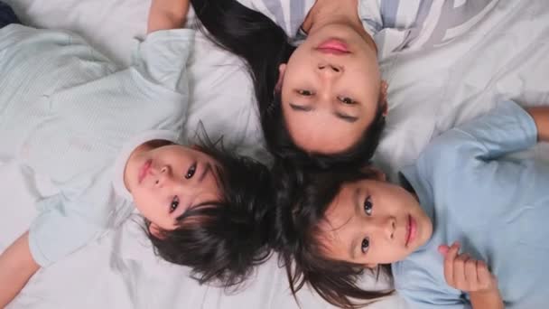 快乐的孩子们和他们的母亲一起玩耍 躺在床上看着相机的头像 在家里玩的开心 — 图库视频影像