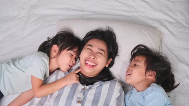 Mutlu Çocukların Evdeki Bir Yatakta Anneleriyle Oynayıp Kameraya Baktıklarının Üst — Stok video