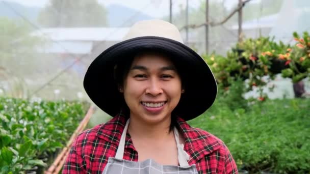 Усміхнений Садівник Фартусі Дивиться Камеру Оранжереї Щаслива Азіатка Доглядає Рослини — стокове відео