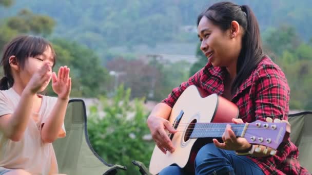 妈妈和孩子们一起弹吉他 在夏令营的帐篷边的椅子上唱歌 一家人在一起度假 — 图库视频影像