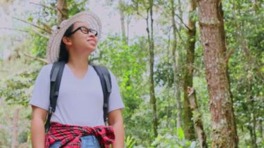 Dişi gezginler, tropik ormandaki yemyeşil ağaçlara bakarak doğanın güzelliğinin tadını çıkarırlar. Sırt çantalı hippi kadın doğanın ortasında bir yolda yürüyor..