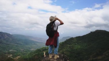 Sırt çantalı bayan yürüyüşçü dağın tepesinde duruyor ve manzaranın tadını çıkarıyor. yolculuk ve başarı kavramı