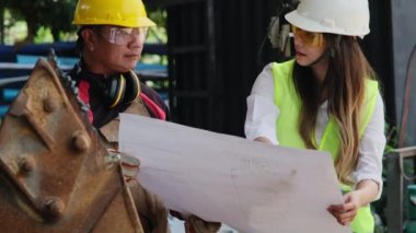 Asian engineering manager and mechanic worker working in a helmet while discussing and inspecting the manufacturing process in the factory.