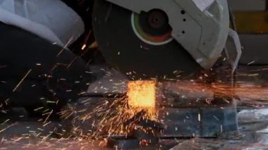 Gözlük ve inşaat eldiveni takan profesyonel adamlar elektrikli çelik kesici makinesiyle ev atölyesinde çalışıyorlar. Metal kesmek kıvılcımları uçurur, yakınlaştırır