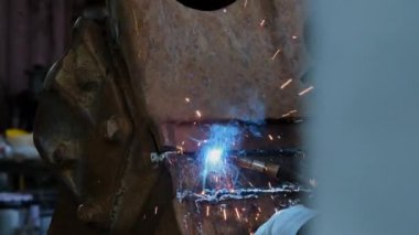 Closeup of a welding machine in work. Worker welds metal with sparks flying.