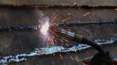 Kaynak makinesinin kapanışı. İşçi kaynak yapar kıvılcımlar saçan metal.