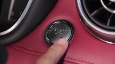 Sürücünün eli arabayı çalıştırmak için düğmeye basıyor. Motorun anahtarsız ateşlemesi başladı. Ulaşım ve teknoloji kavramı